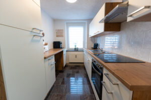 Gut ausgestattete, helle Küche mit Elektrogeräten und Kaffeemaschine