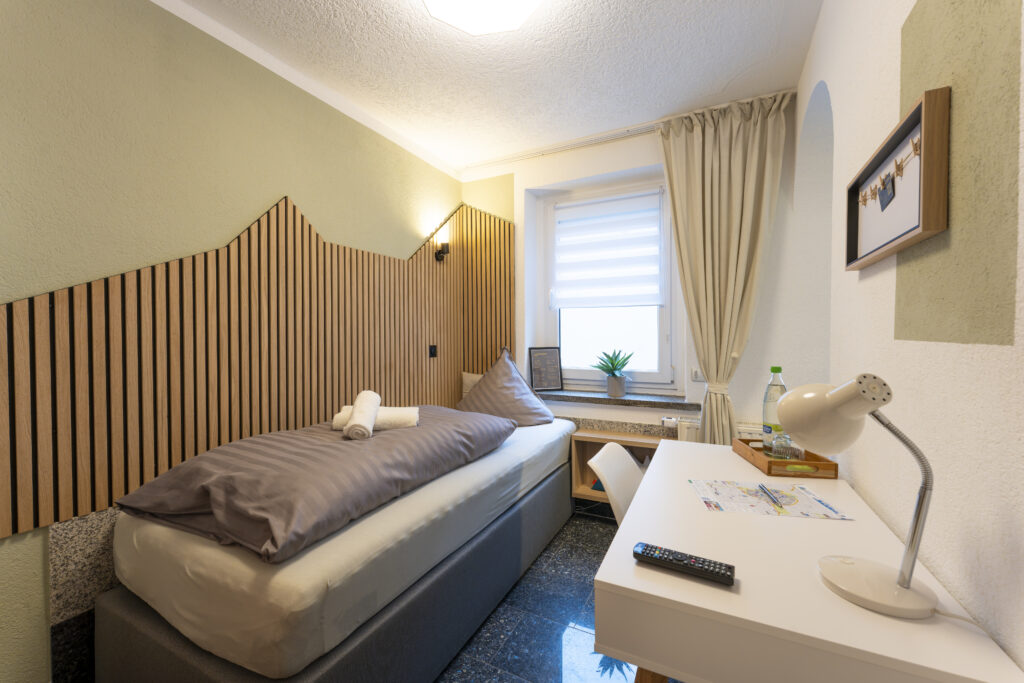 Blick in Zimmer 6 (Einzelzimmer): Boxspringbett und Schreibtisch