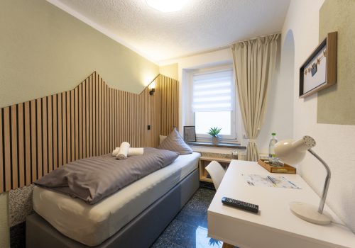 Blick in Zimmer 6 (Einzelzimmer): Boxspringbett und Schreibtisch